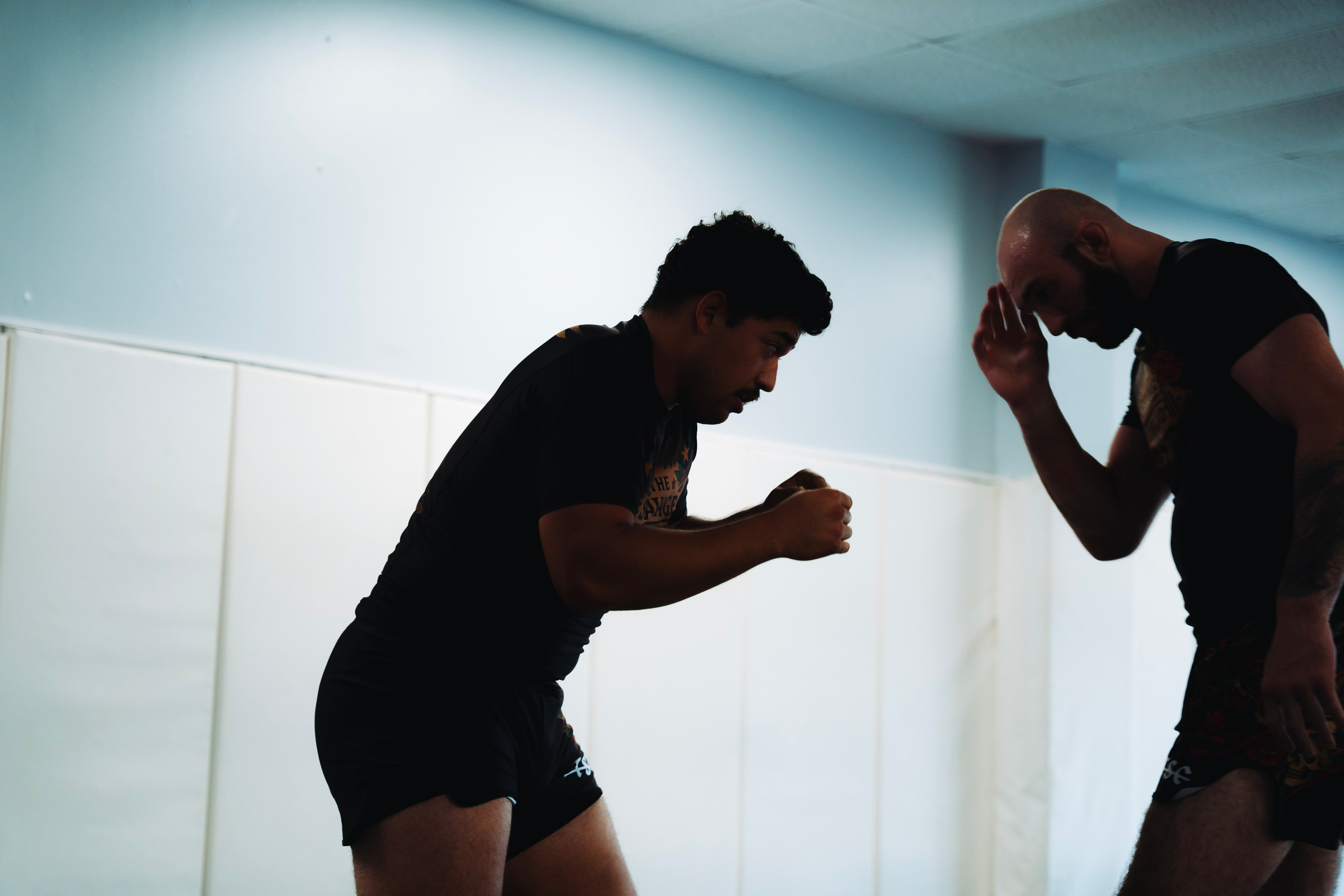 Two men in a room, one in silhouette, the other with a light source.